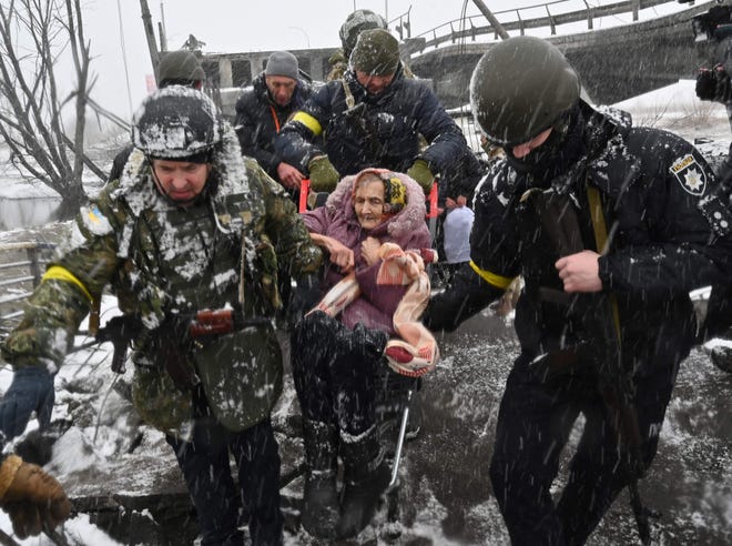 Ukraynalı askerler, 8 Mart 2022'de Kiev'in kuzeybatısındaki Irbin şehrinin tahliyesi sırasında yaşlı bir kadının yıkılan bir köprüyü geçmesine yardım ediyor.