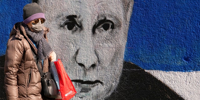 12 Mart 2022 Cumartesi, Sırbistan, Belgrad'da Rusya Devlet Başkanı Vladimir Putin'i tasvir eden bir duvar resminin yanından geçen bir kadın. 