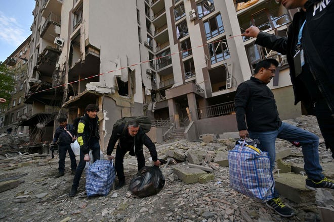 TOPSHOT - Sakinler, Rusya'nın Ukrayna'yı işgali sırasında 29 Nisan 2022'de Kiev'de Rus saldırılarının ardından yıkılan bir binadan çıkarken eşyalarını taşıyorlar.  - Rus saldırıları, BM Genel Sekreteri Antonio Guterres'in ziyareti sırasında 28 Nisan akşamı Kiev'i vurdu.