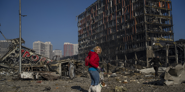 Irina Zubchenko, Pazartesi günü Ukrayna'nın Kiev kentinde bir alışveriş merkezinin bombalanmasının yol açtığı yıkımın ortasında köpeği Max'i gezdiriyor.