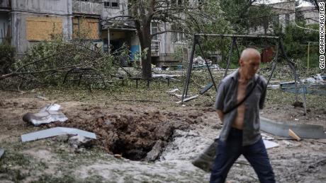 Yerel bir sakin, 13 Haziran 2022'de Ukrayna'nın Bakhmut kentinde Rusya'nın Ukrayna'yı işgali sırasında bir füze saldırısında yıkılan bir apartmanın yanından geçiyor. 