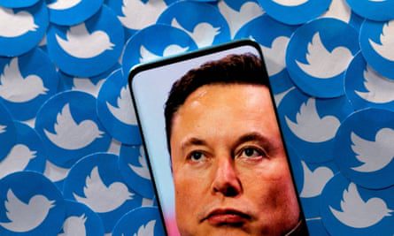 Elon Musk'ın akıllı telefondaki, basılı Twitter logolarının üzerinde duran görüntüsü