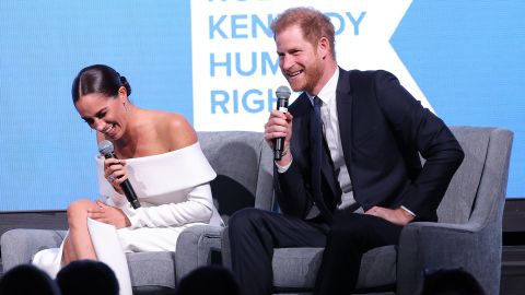 Etkinlik sırasında sahnede Kerry Kennedy ile sohbet eden çift gülüyor. 